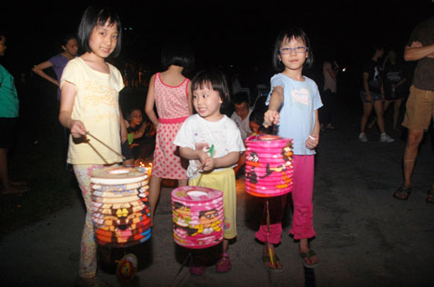 Children carry colourful paper lanterns