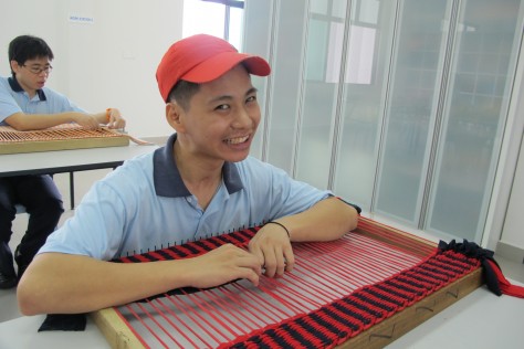 19-year old Chen Yee How weaving a floor rug for sale in the thrift shop