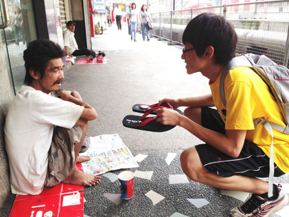 Ang Chee Poh offering a pair of slippers to beggar