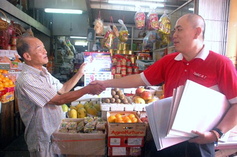 Lau Weng San handing out 2014 calendars to market traders in SEA Park