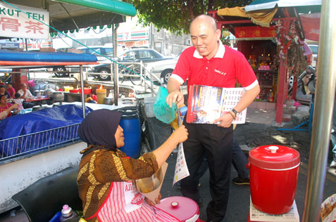 Lau Weng San handing out calendar to nasi lemak seller in SEA Park