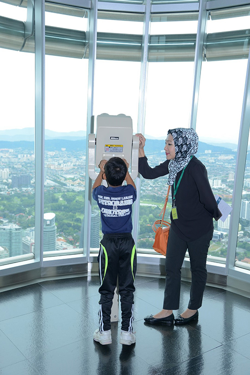 Siti Shazlina Shamsiruddin, Manager, Corporate Social Responsibility (right) with a student checking out the KL skyline from the Petronas Twin Towers Skybridge.
