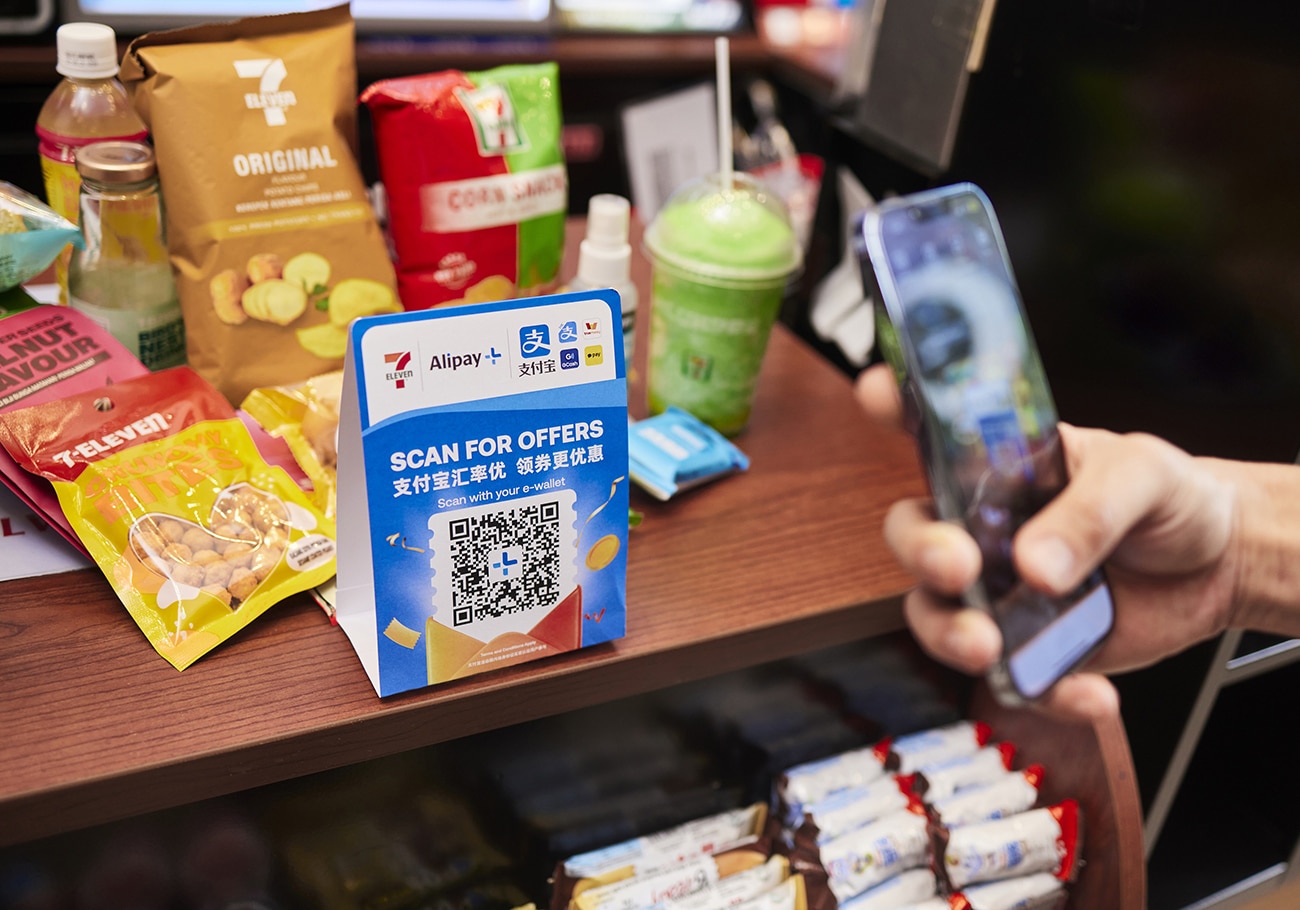 Tourists in Singapore using Alipay+ to pay for street food, highlighting the platform's convenience and global reach.